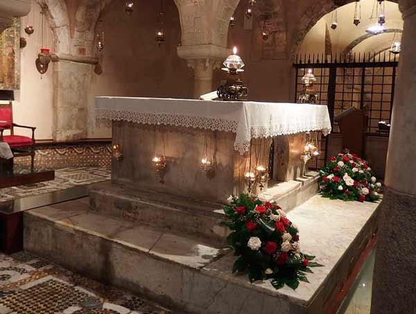 Sankt Nikolaus grav i marmor med rosenbuketter framför