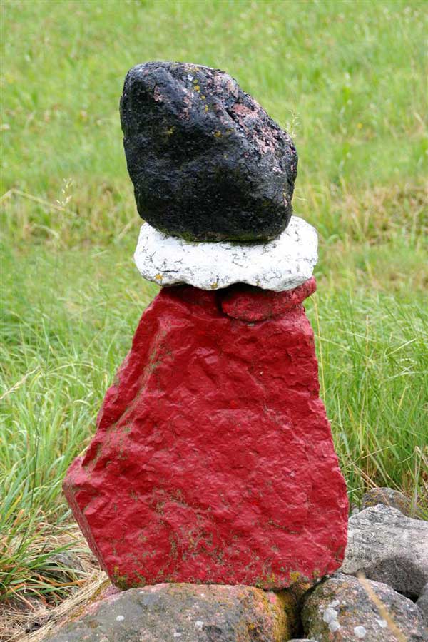 Fotografi föreställande Röstensgubben, tre stenar i rött, vitt och svart placerade på varandra